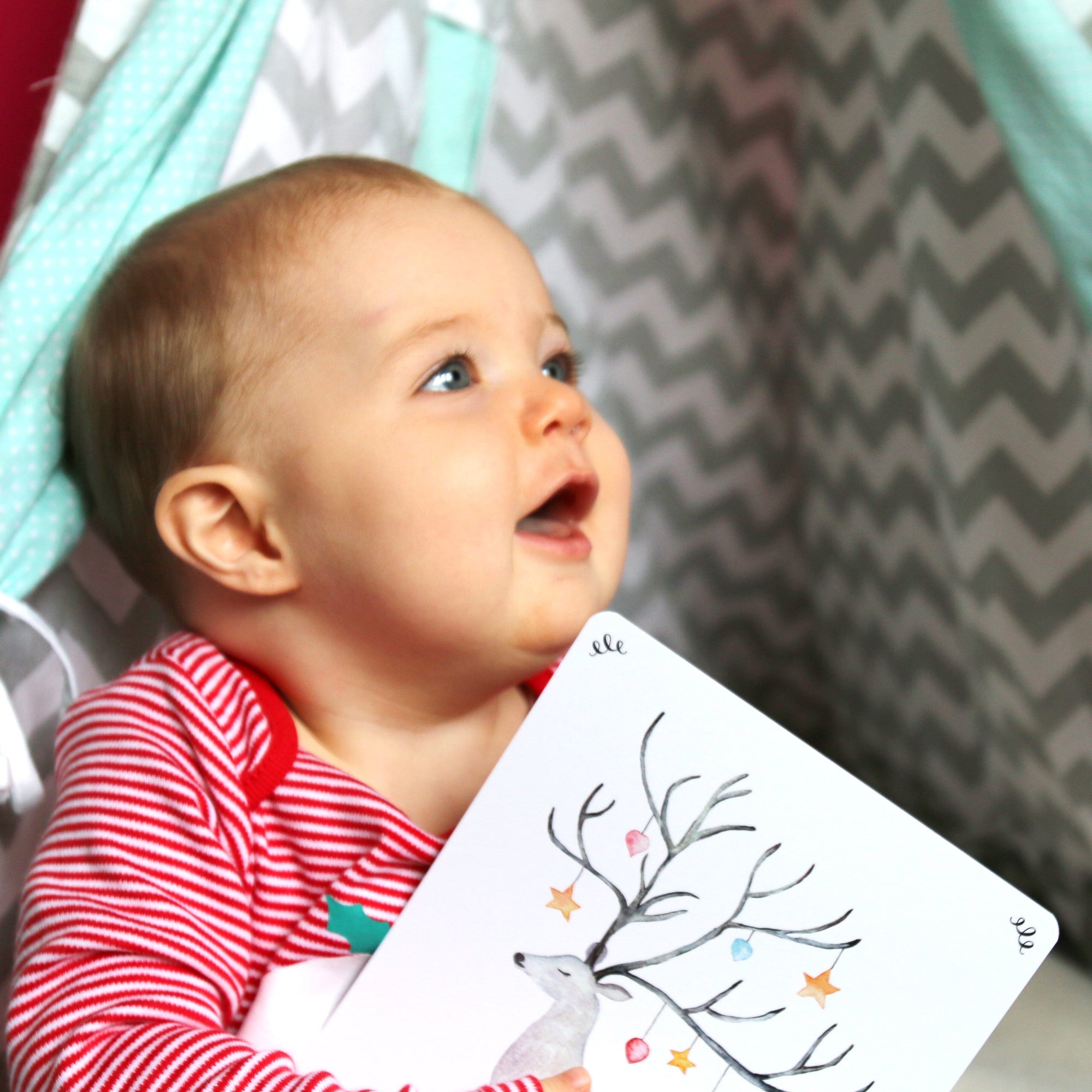 Smiling baby holding a painted reindeer print