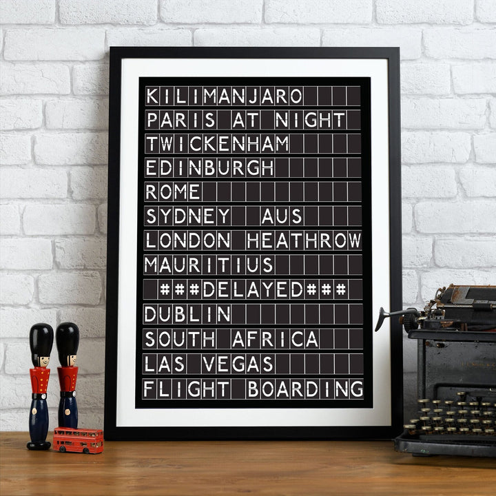 Black framed black and white print in the style of an airport departures board