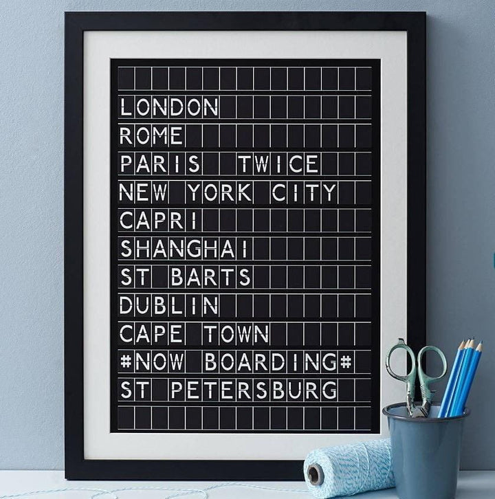 Black framed black and white print in the style of an airport departures board