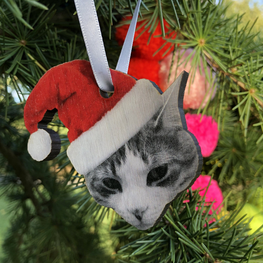 personalised custom bauble Christmas decoration of a cat wearing a Santa hat hanging from a satin white ribbon. Perfect for Secret Santa gifts and cat lovers.