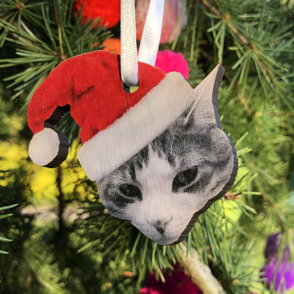 personalised custom bauble Christmas decoration of a cat wearing a Santa hat hanging from a satin white ribbon. 