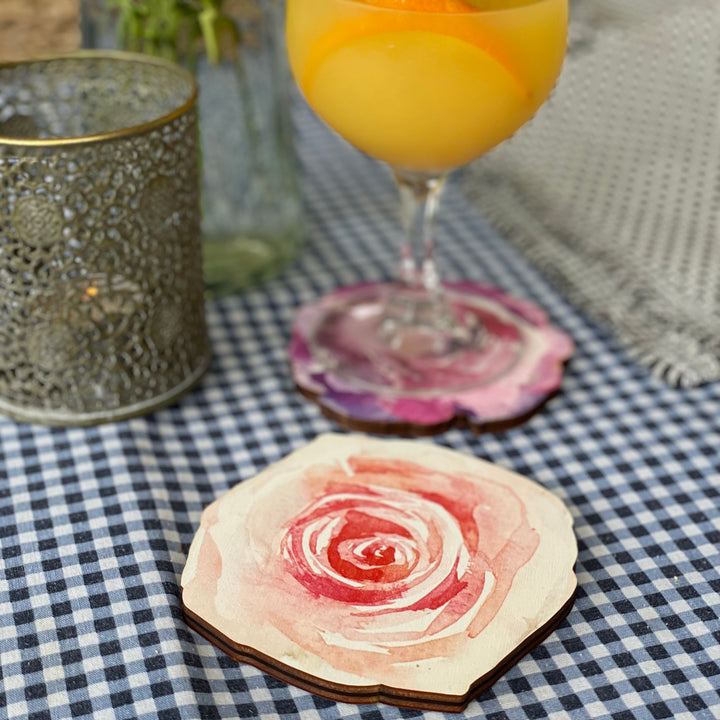 A delightful scene featuring a refreshing cocktail in a glass, resting on a vibrant pink rose-patterned wooden coaster.