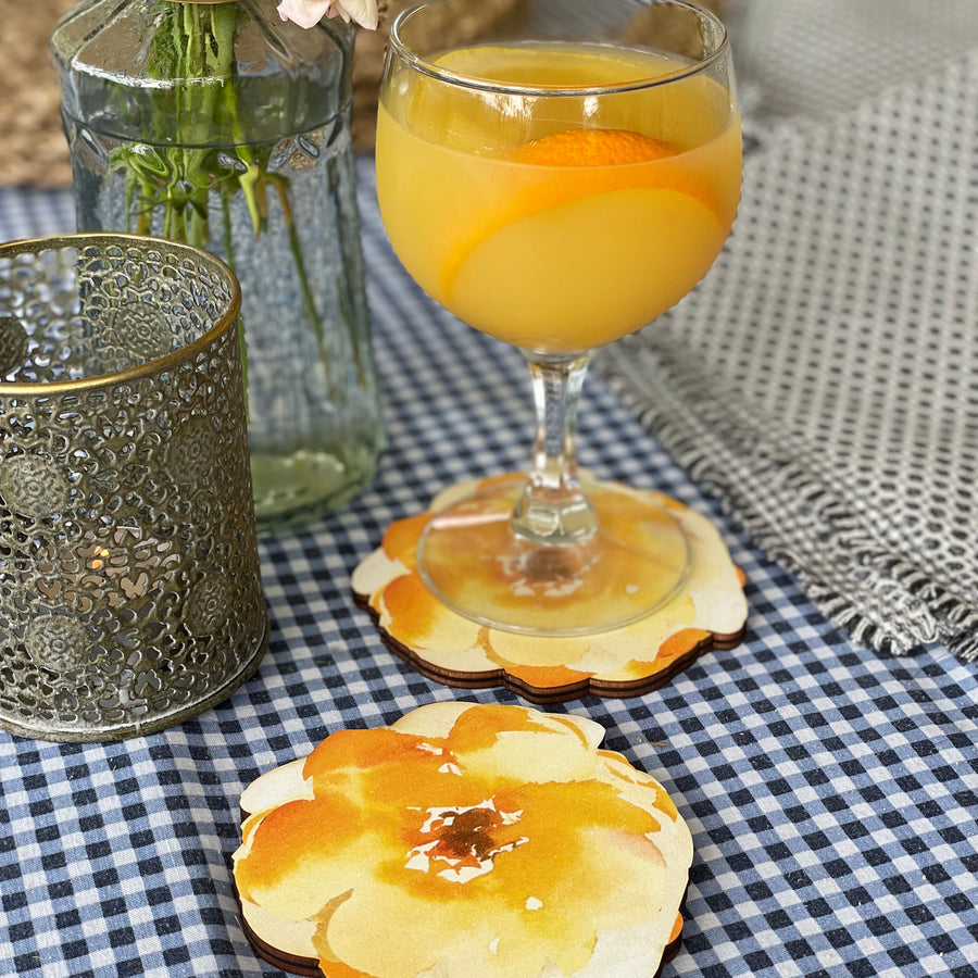 A delightful scene featuring a refreshing cocktail in a glass, resting on a floral-patterned wooden coaster.