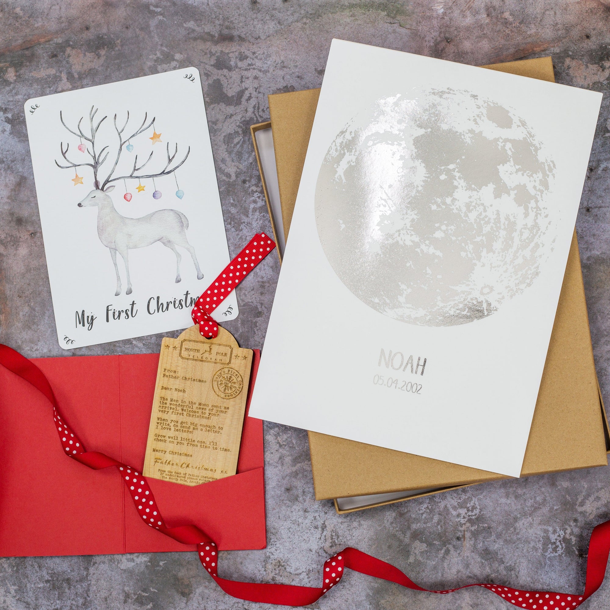 Baby's Letterbox gift with a silver moon personalised print, hand painted print of a reindeer and a luggage tag shaped wooden decoration engraved with a typed message from Father Christmas