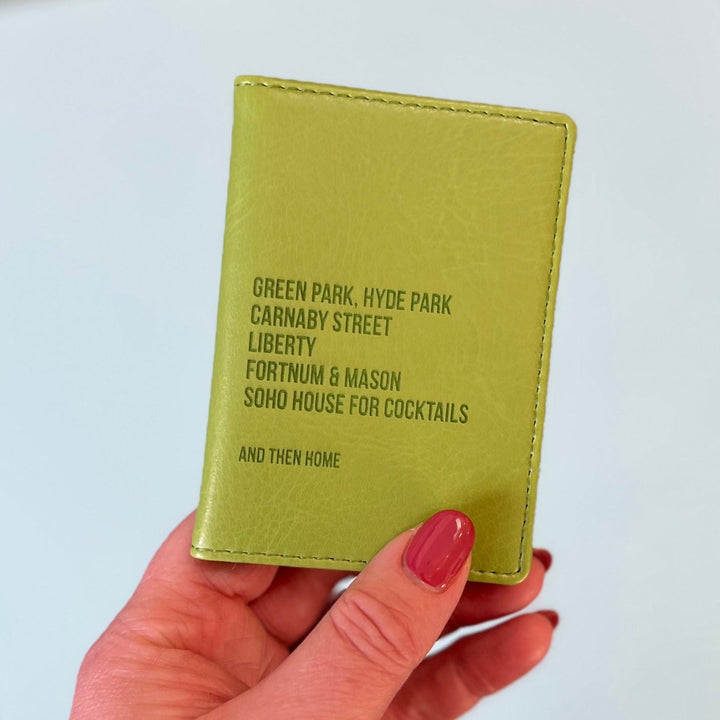 A womans hand holds a green custom ID holder/credit card holder. The front of the slim wallet has been personalised with six lines of bespoke text. The first five lines list favourite shopping destinations in London. The last line says And Then Home.