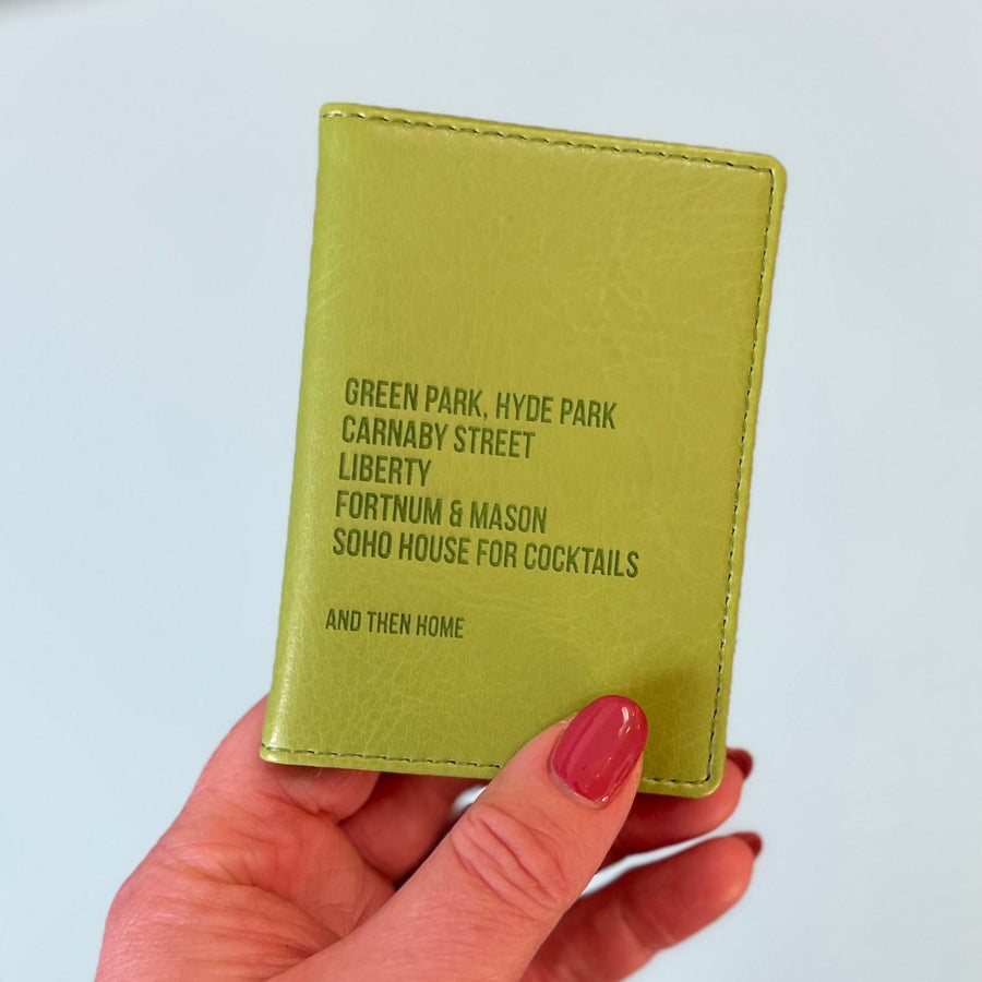 A womans hand holds a green custom ID holder/credit card holder. The front of the slim wallet has been personalised with six lines of bespoke text. The first five lines list favourite shopping destinations in London. The last line says And Then Home.