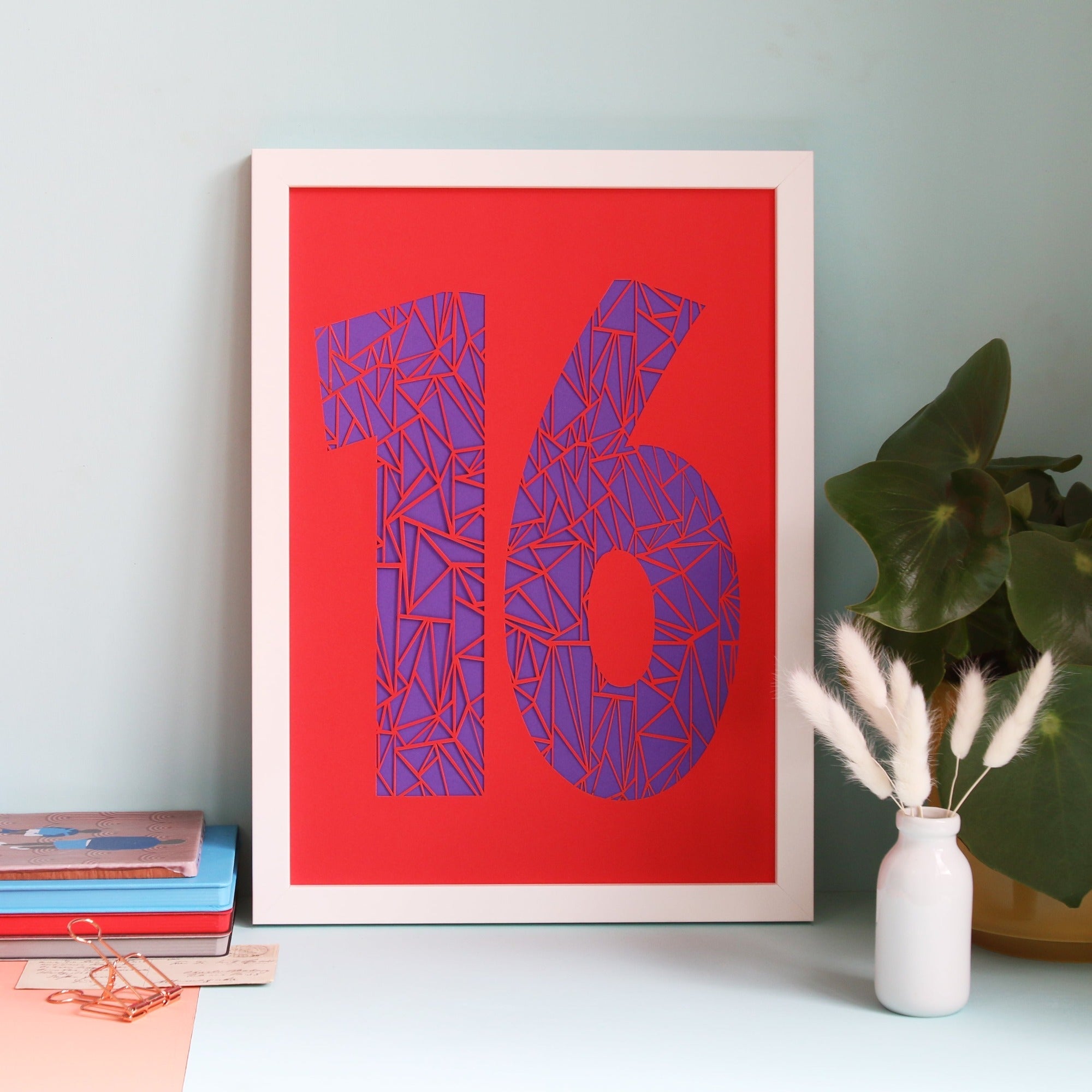 Bright red papercut of the number 16 with a purple background.