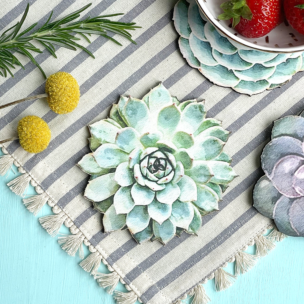 Close-up of a succulent-shaped wooden coaster on a striped fabric with decorative elements.