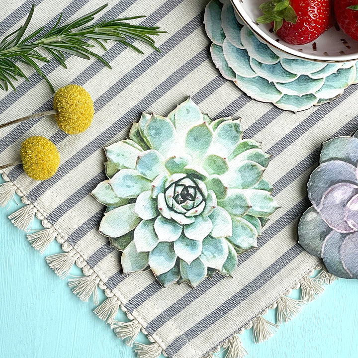 Close-up of a succulent-shaped wooden coaster on a striped fabric with decorative elements.