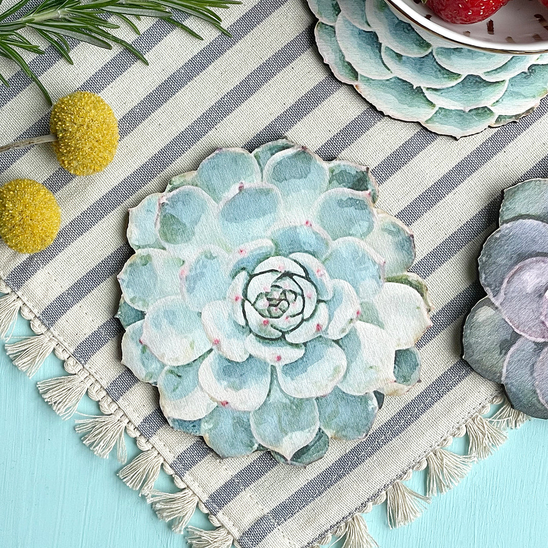 Close-up of a succulent-shaped wooden coaster on a striped fabric with decorative elements.