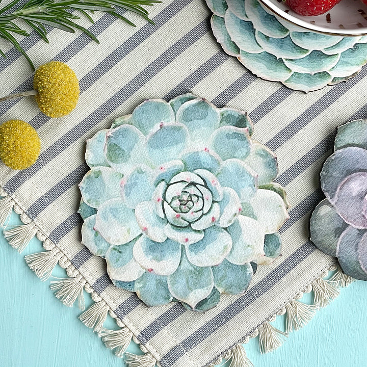 Close-up of a succulent-shaped wooden coaster on a striped fabric with decorative elements.
