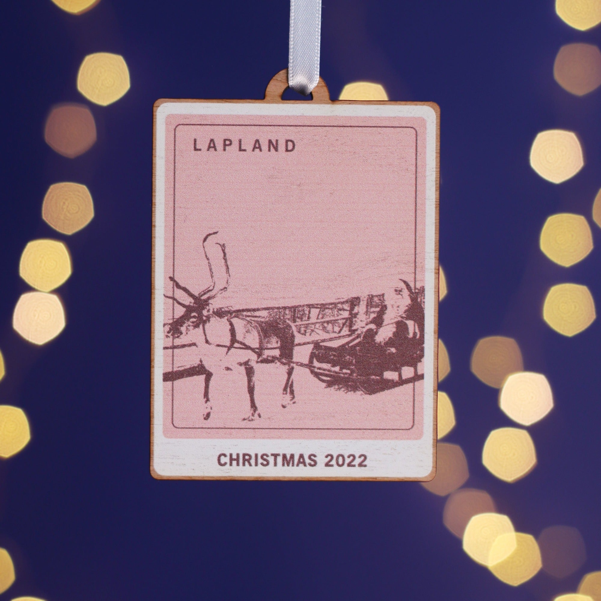 Wooden Christmas decoration with a picture representing Lapland printed on it.