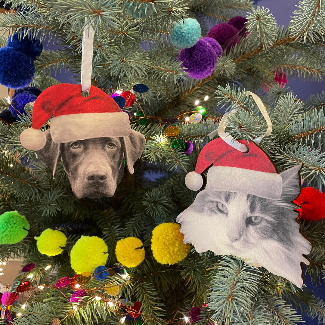 Wooden cat and dog face bauble with festive hats, rustic Christmas tree ornament for families with pets.