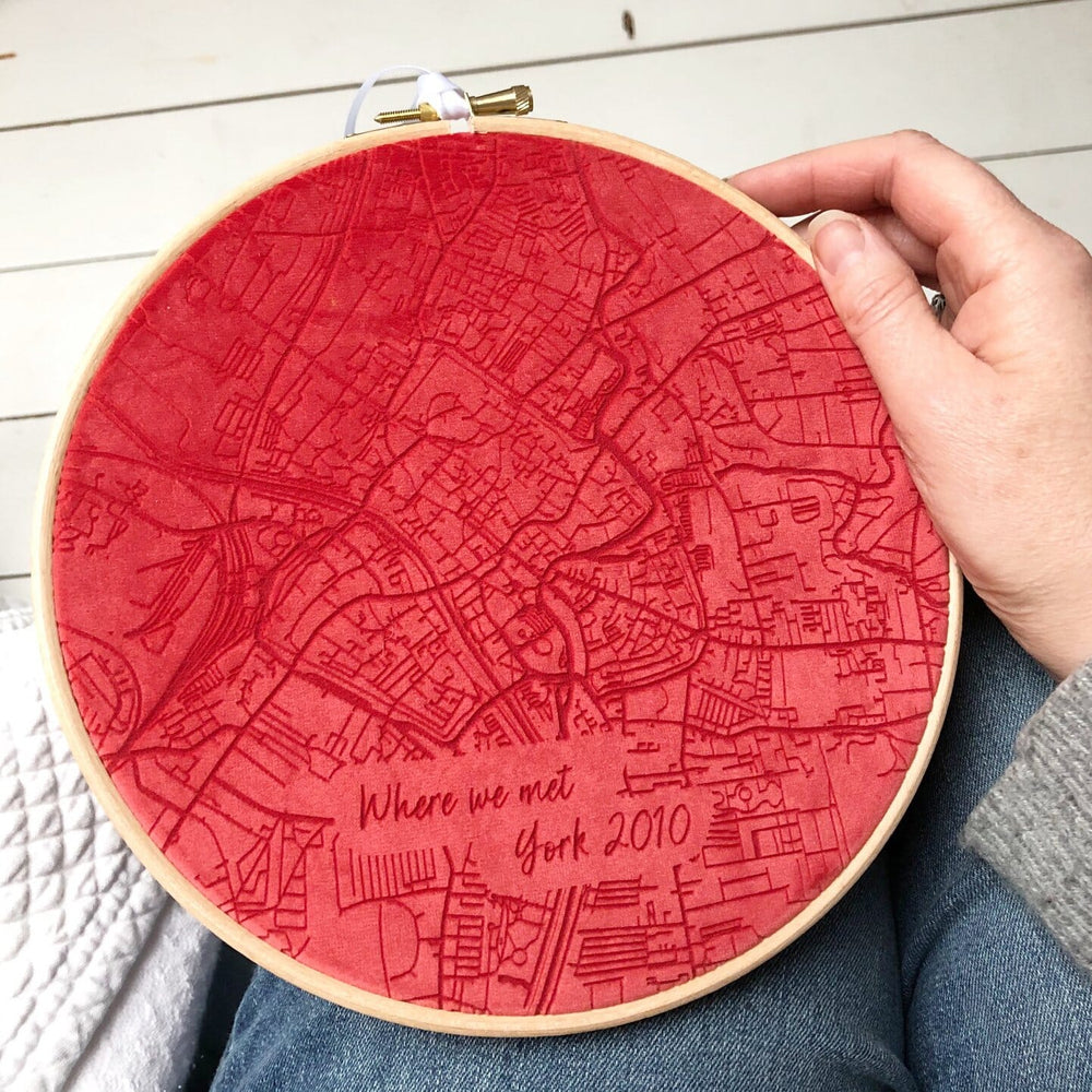  A hand holding a red velvet embroidery hoop with a map of York, England embroidered on it. The text "Where we met. York 2010" is embroidered at the bottom.